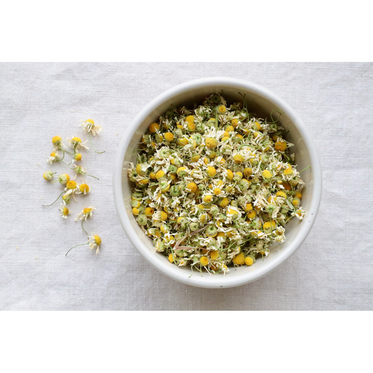 Organic hand-harvested chamomile on display in bowl and on cloth