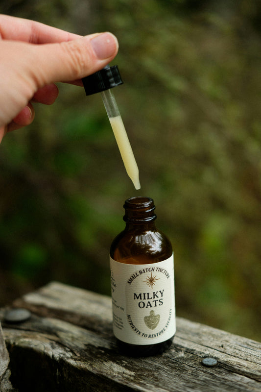 A dropper of milky oats tincture over an amber bottle labelled Milky Oats at La Ferme À Ciel Sur Mer