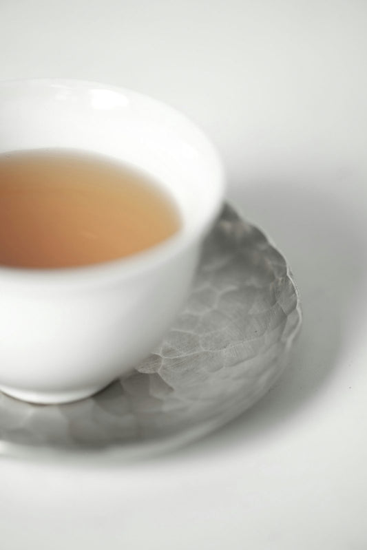 A cup of freshly brewed golden chamomile tea on a saucer